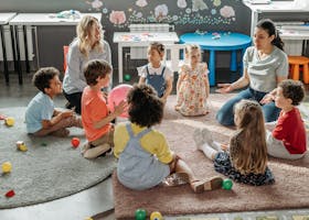 Children in circle time with teachers, engaging in a kindergarten classroom activity.